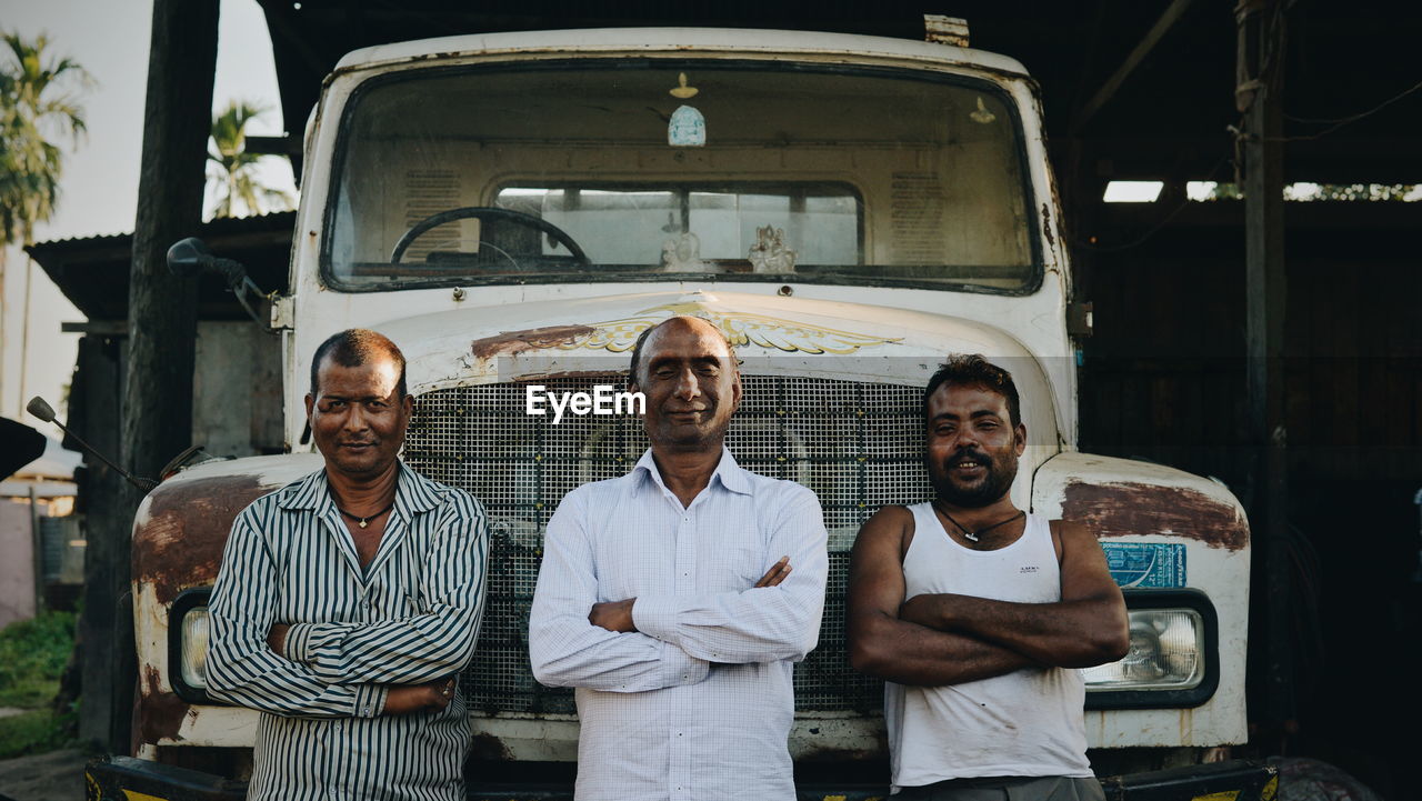 PORTRAIT OF FRIENDS STANDING AGAINST BUS