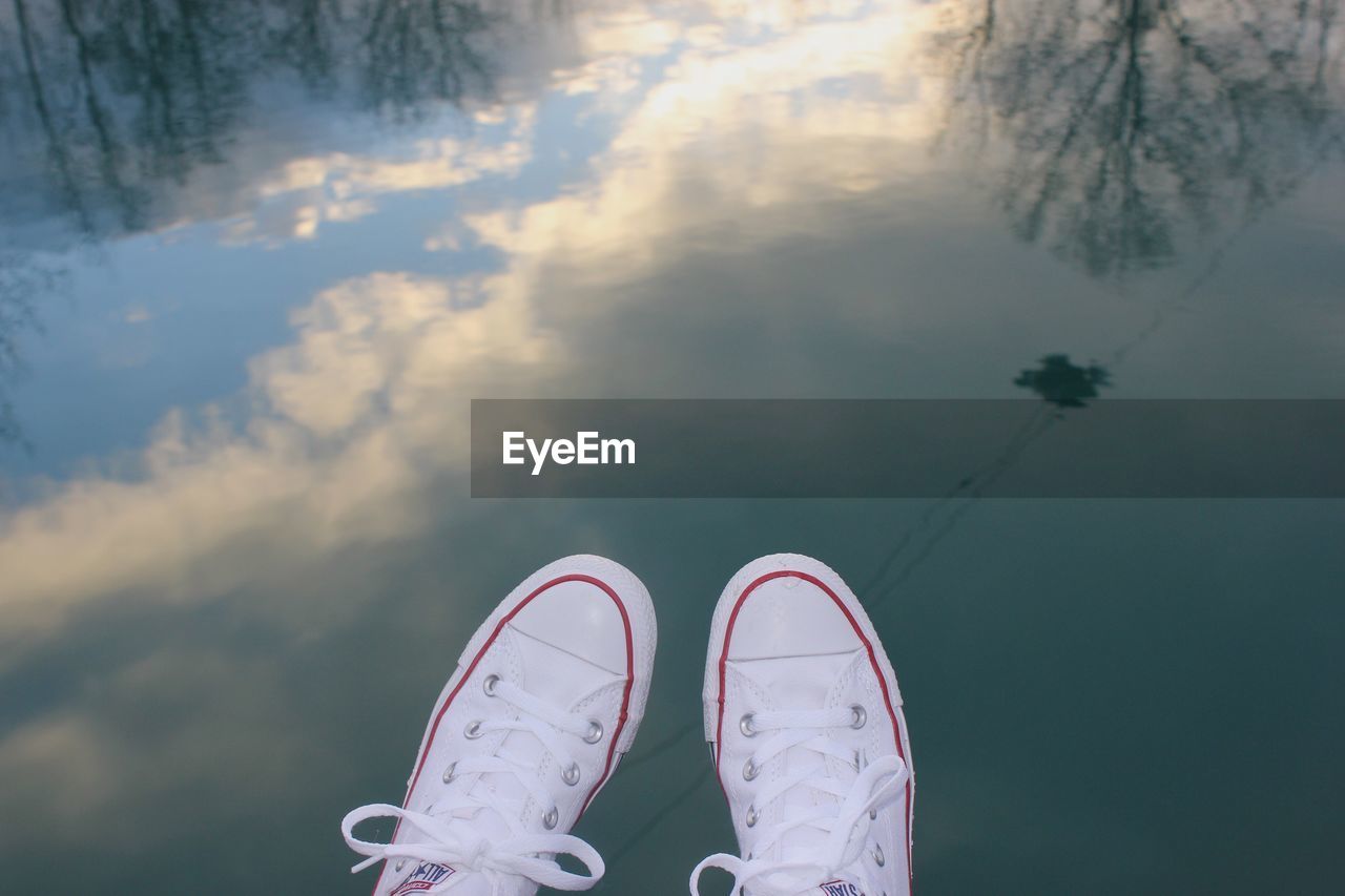 Low section of person wearing shoes over lake