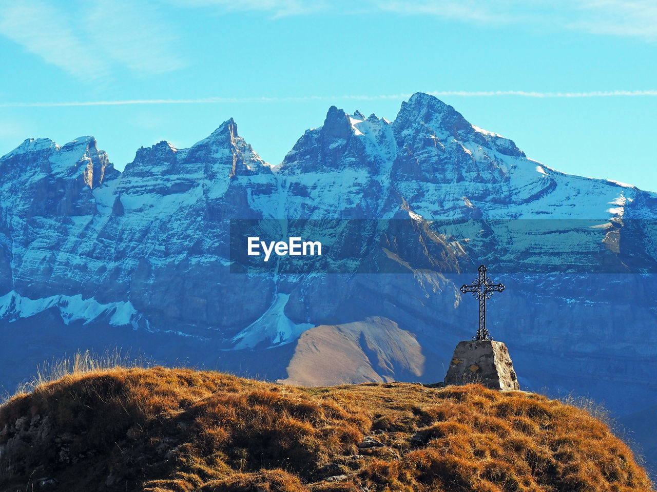 Cross shape on hill against snowcapped mountains