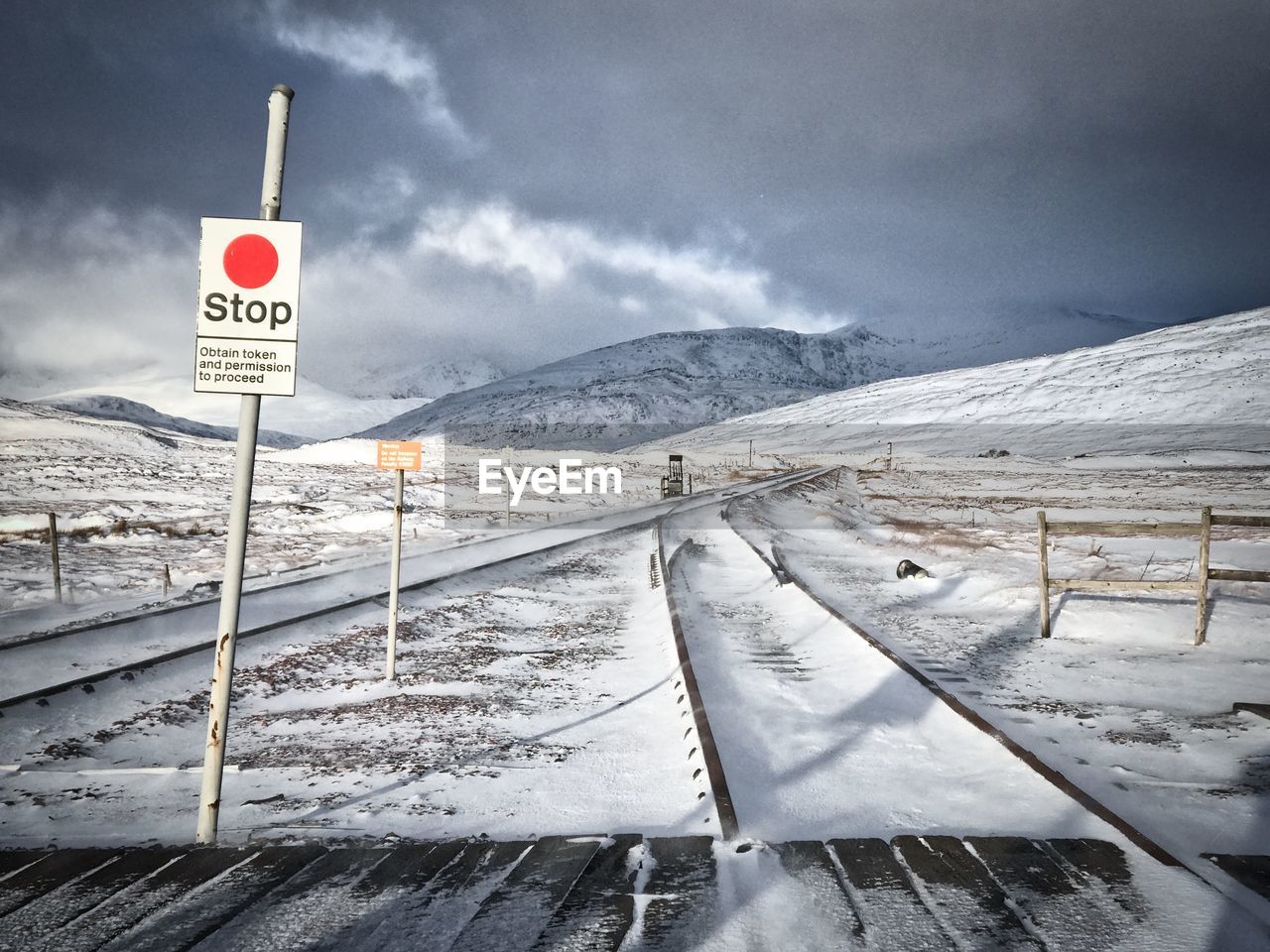 ROAD SIGN ON SNOW COVERED MOUNTAINS AGAINST SKY