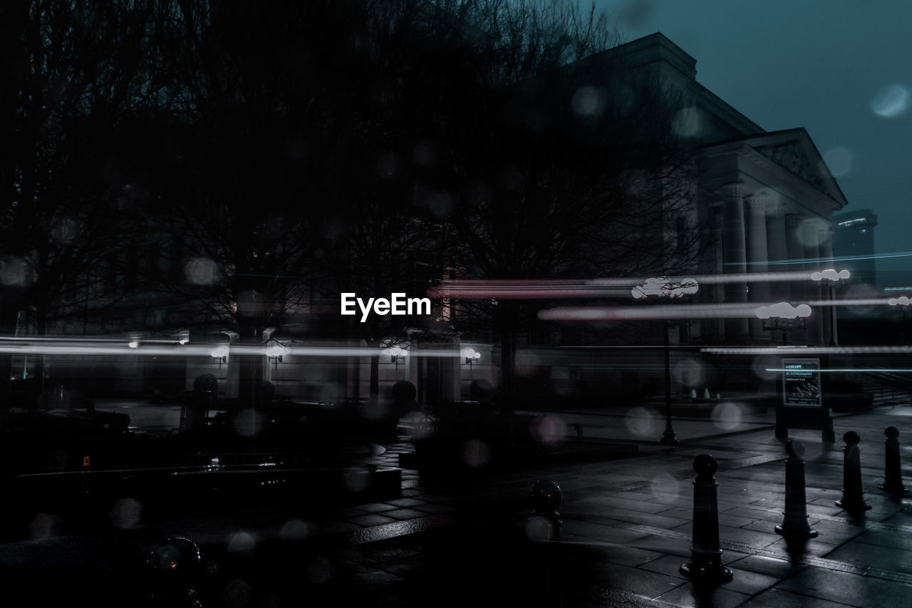 ILLUMINATED BUILDINGS BY STREET DURING RAINY SEASON