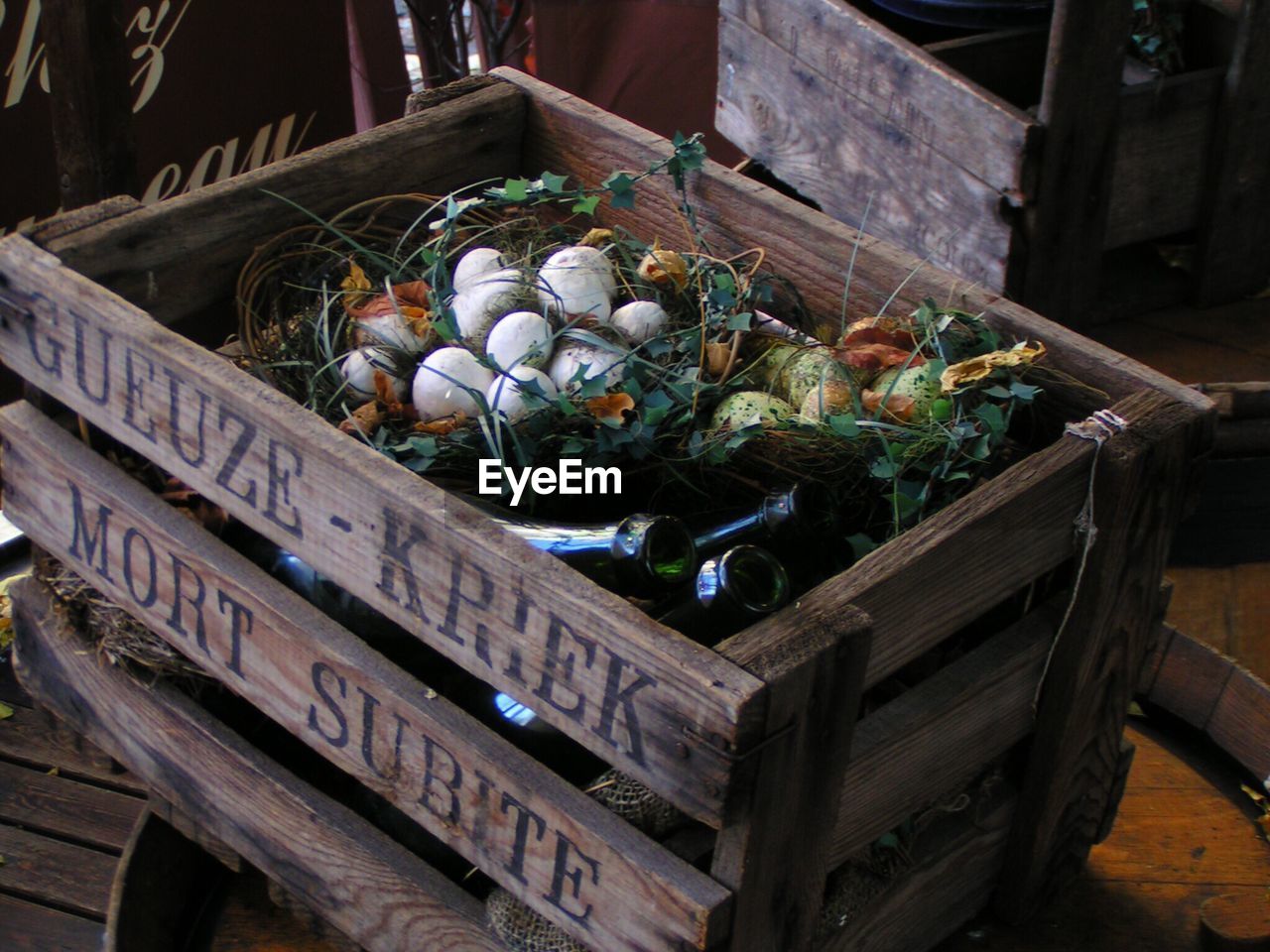 High angle view of eggshells and glass bottles in wooden crate