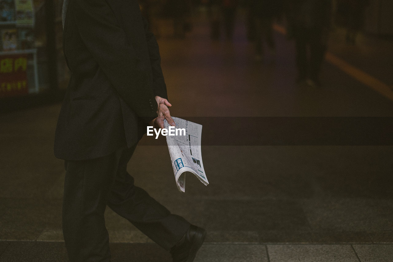 Man holding newspaper while walking outdoors