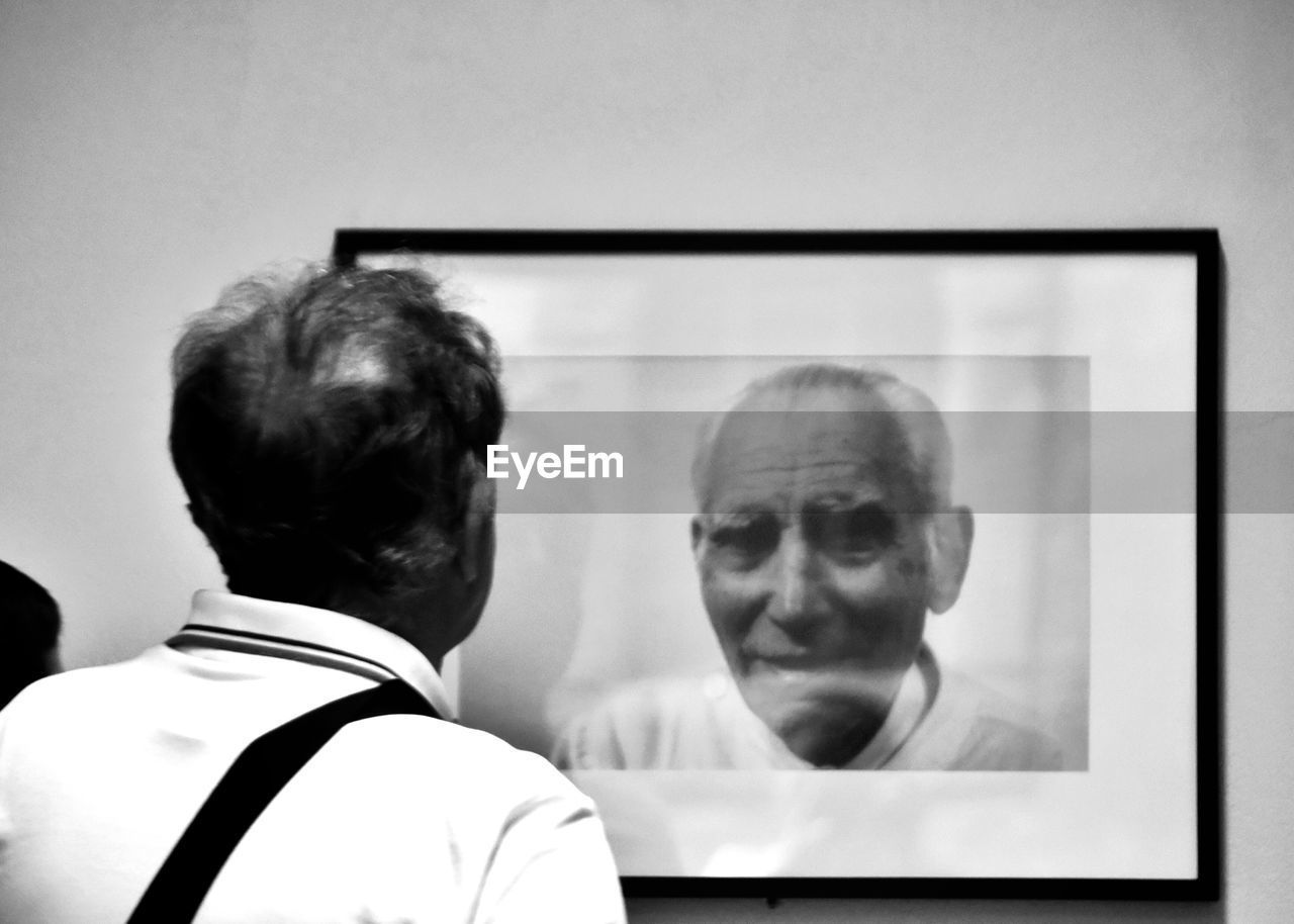 REAR VIEW OF MAN AND CLOSE-UP OF COMPUTER IN BATHROOM