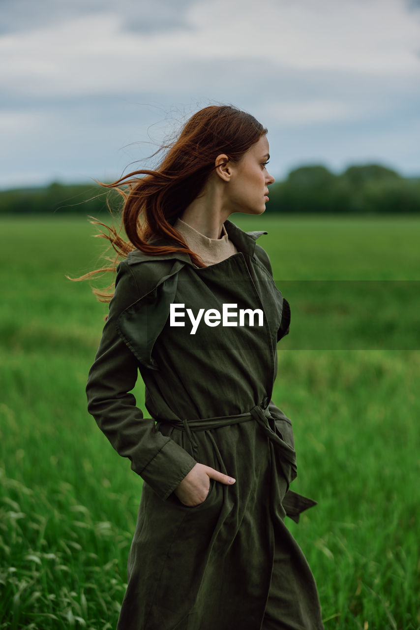 Confident young woman with hand in pocket on grass