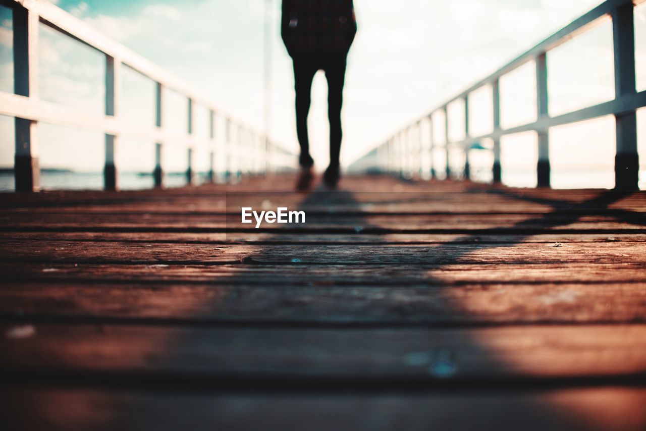 Low section of man standing on footbridge