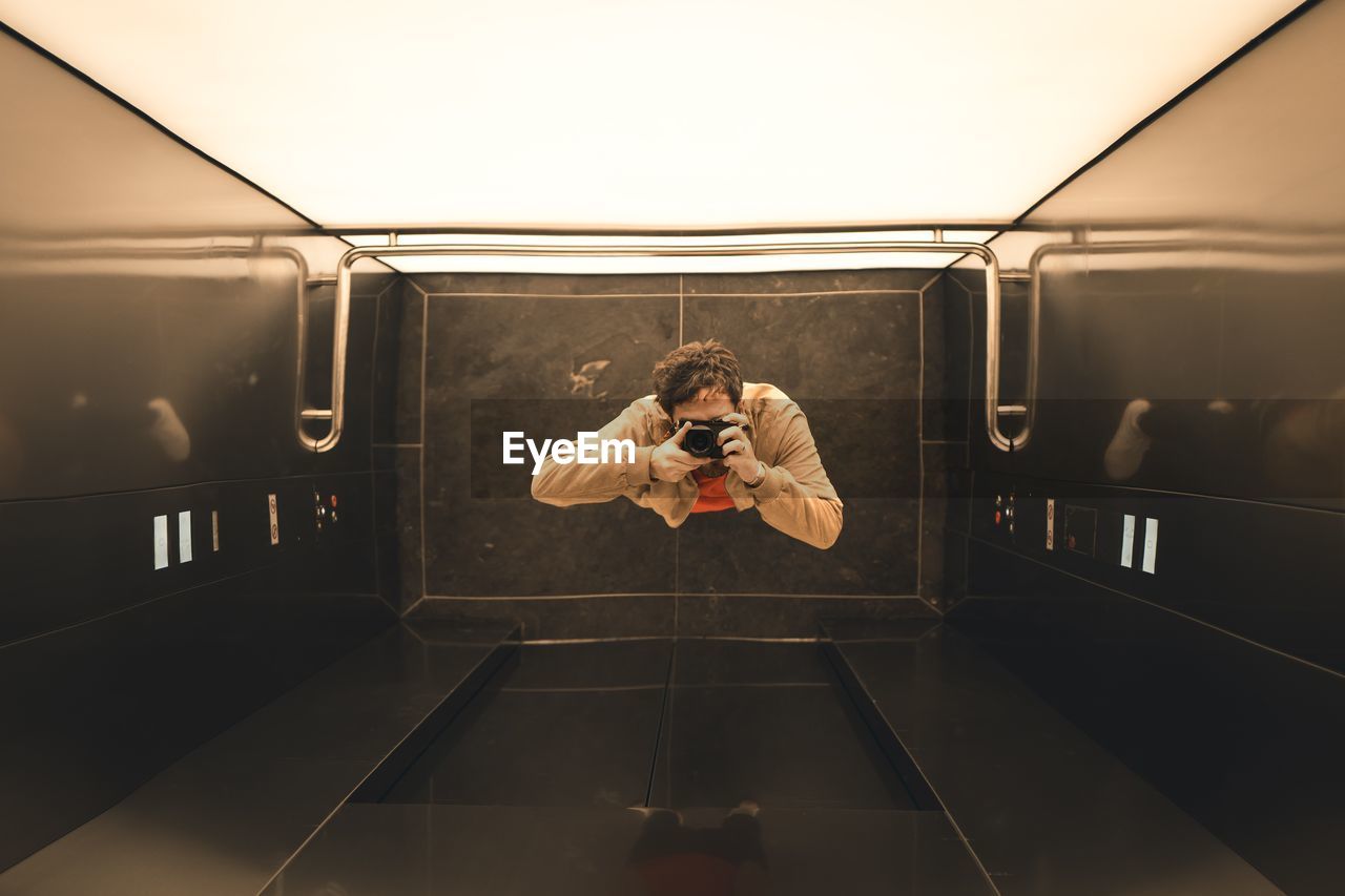 Directly above shot of man photographing with camera in elevator