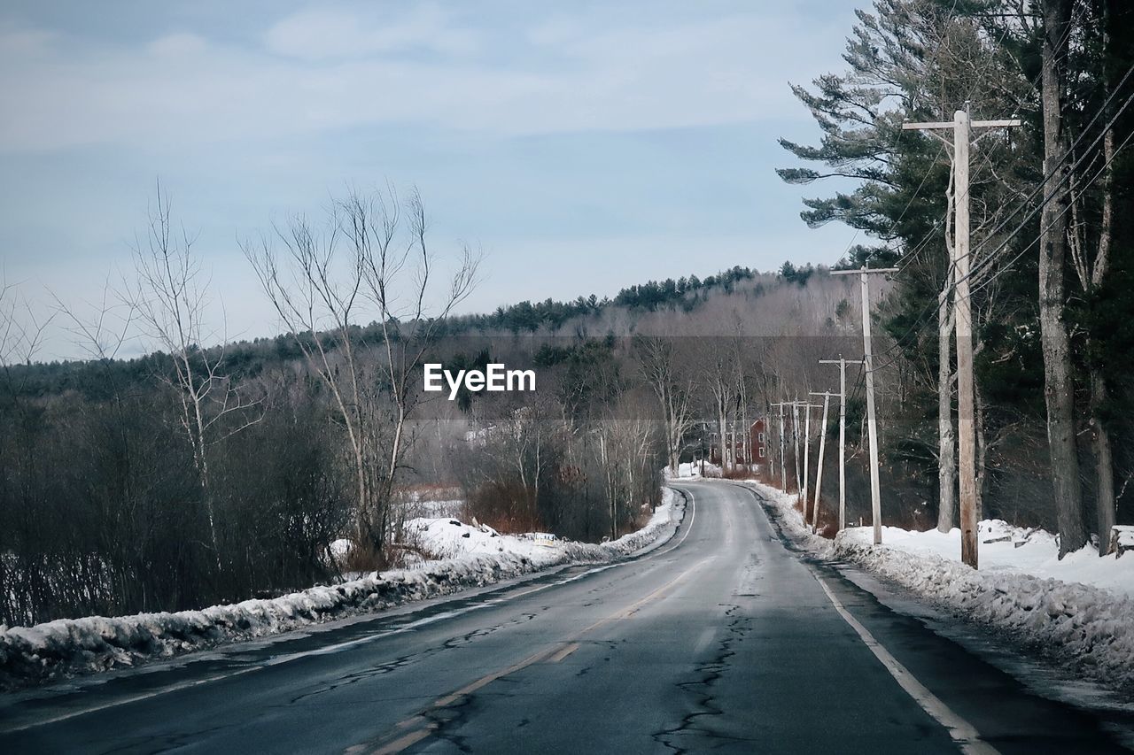 Road amidst trees against sky during winter