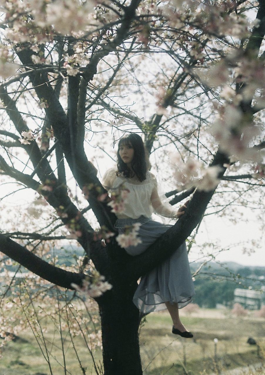 tree, plant, spring, one person, flower, adult, women, nature, branch, young adult, full length, blossom, day, outdoors, leisure activity, beauty in nature, lifestyles, female, clothing, flowering plant, standing, cherry blossom, casual clothing, front view, looking, hairstyle, three quarter length, emotion, dress, long hair