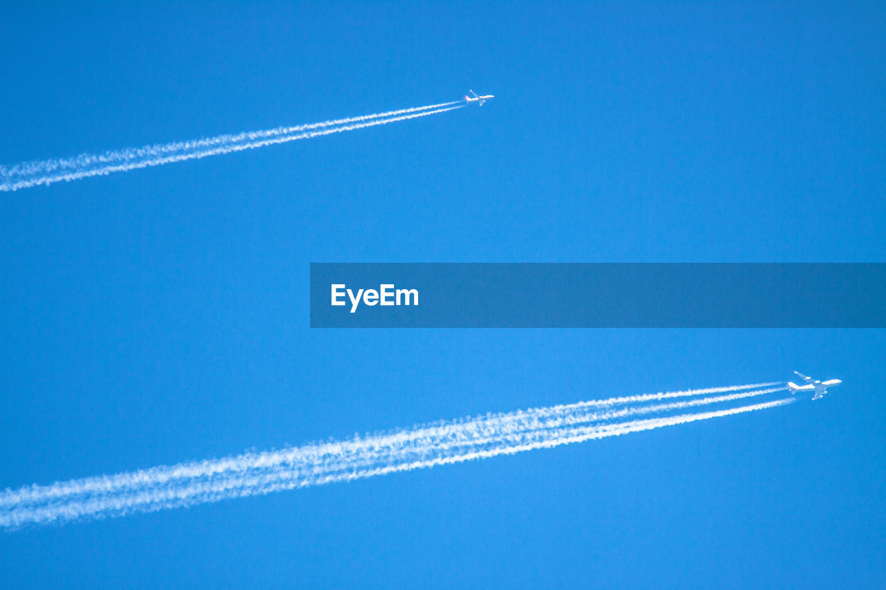 Low angle view of airplanes at airshow against blue sky