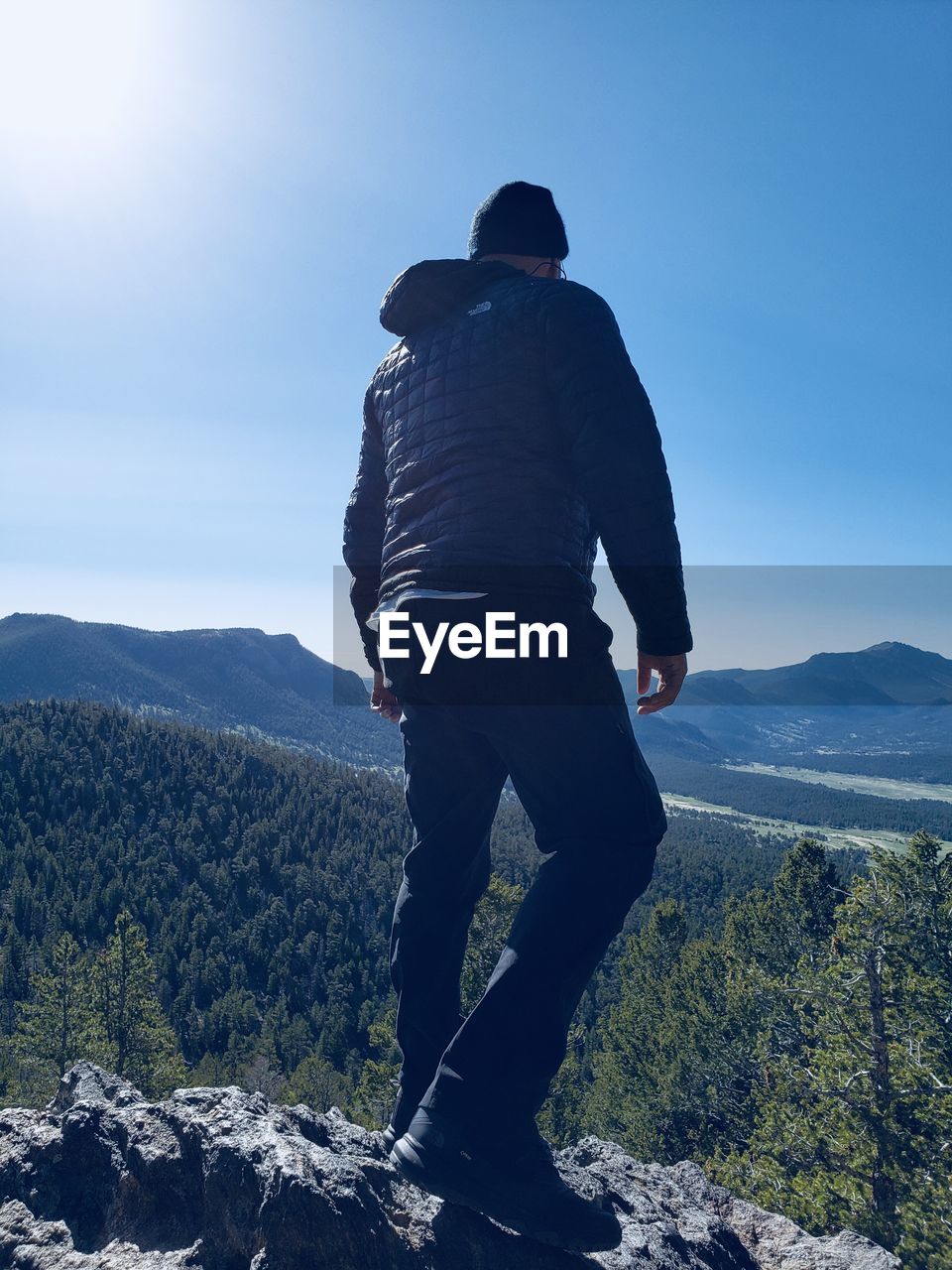 Rear view of man standing on mountain against clear sky