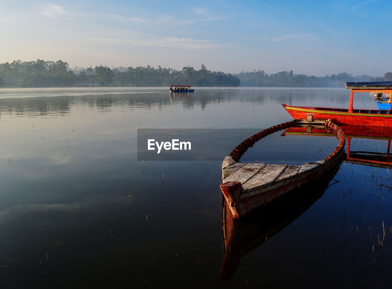 Boat moored in lake against sky