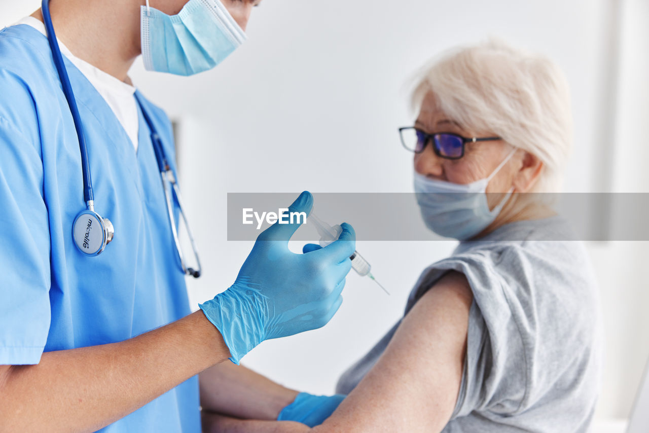 Doctor wearing mask vaccinating patient