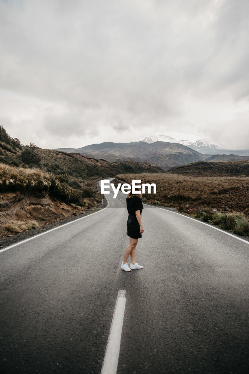 Woman standing on road against sky