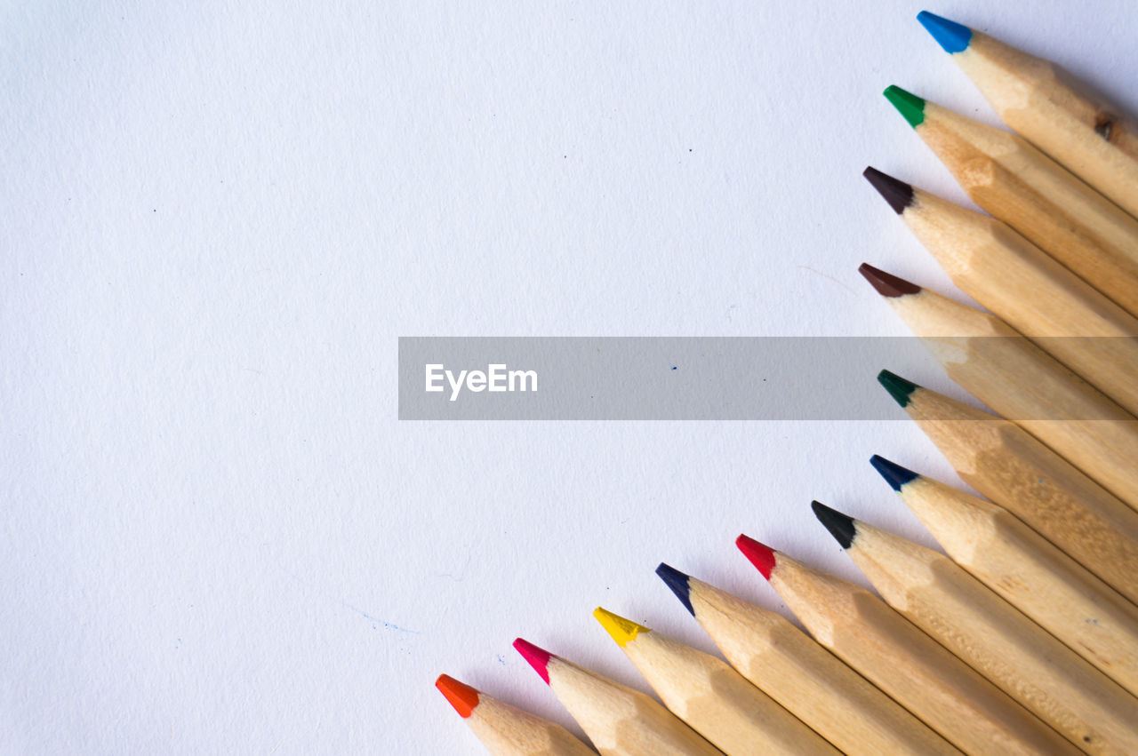 high angle view of colored pencils against white wall