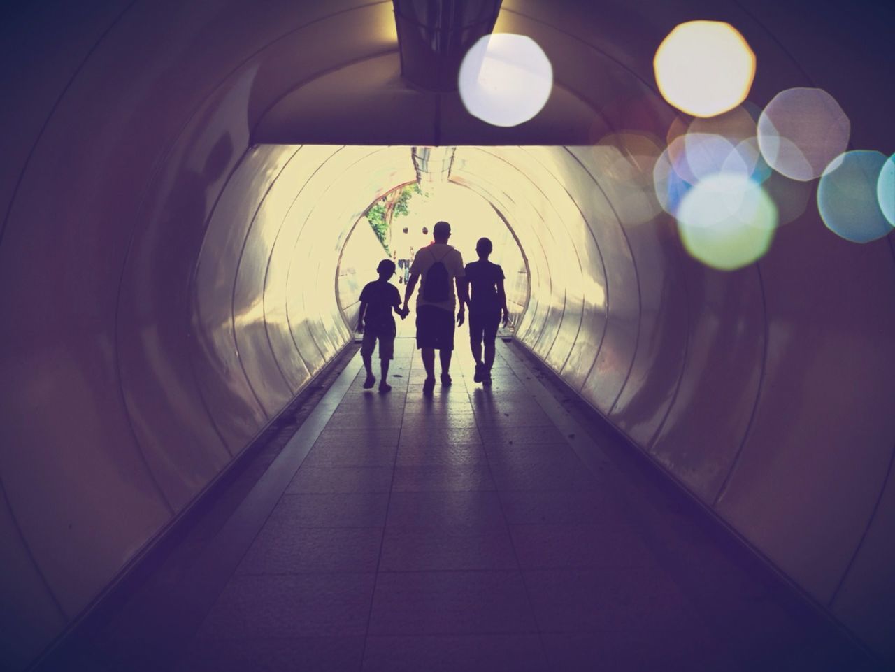 Rear view of people in illuminated tunnel