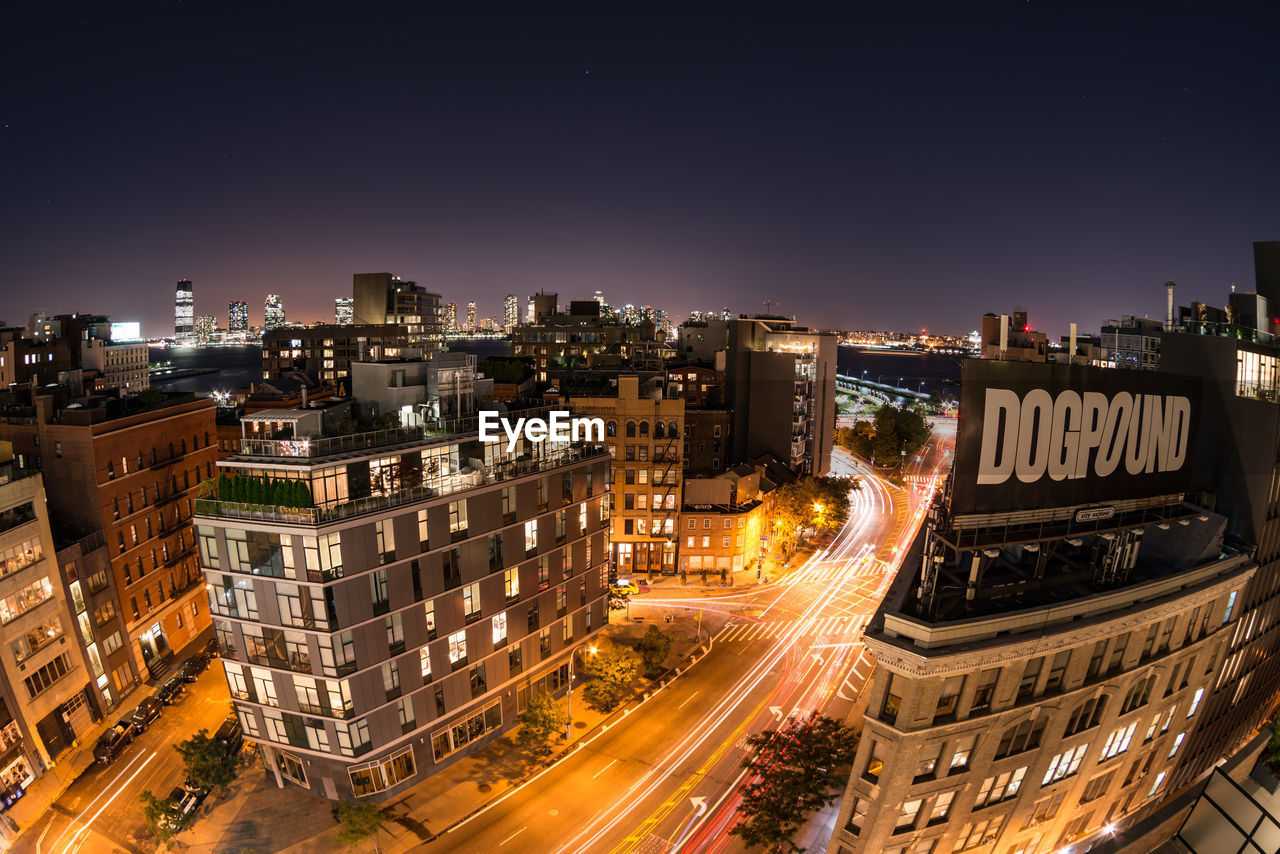 HIGH ANGLE VIEW OF ILLUMINATED CITY STREET AT NIGHT