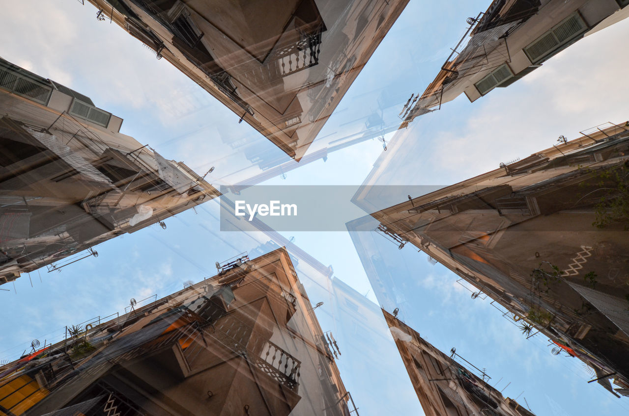 Directly below shot of modern buildings seen through glass against sky in city