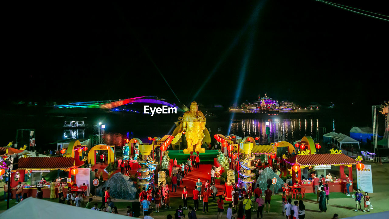 PEOPLE IN AMUSEMENT PARK AGAINST SKY AT NIGHT