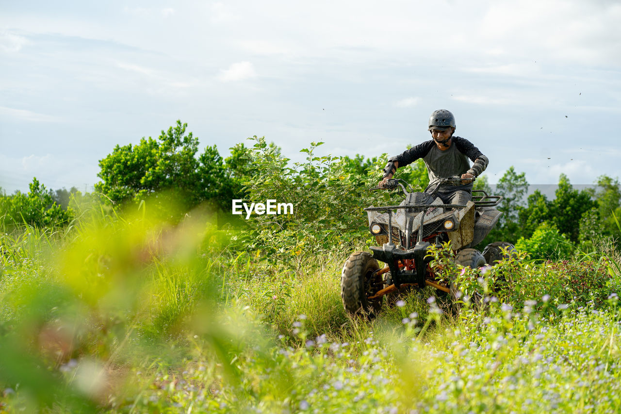 Man riding atv on plants against sky