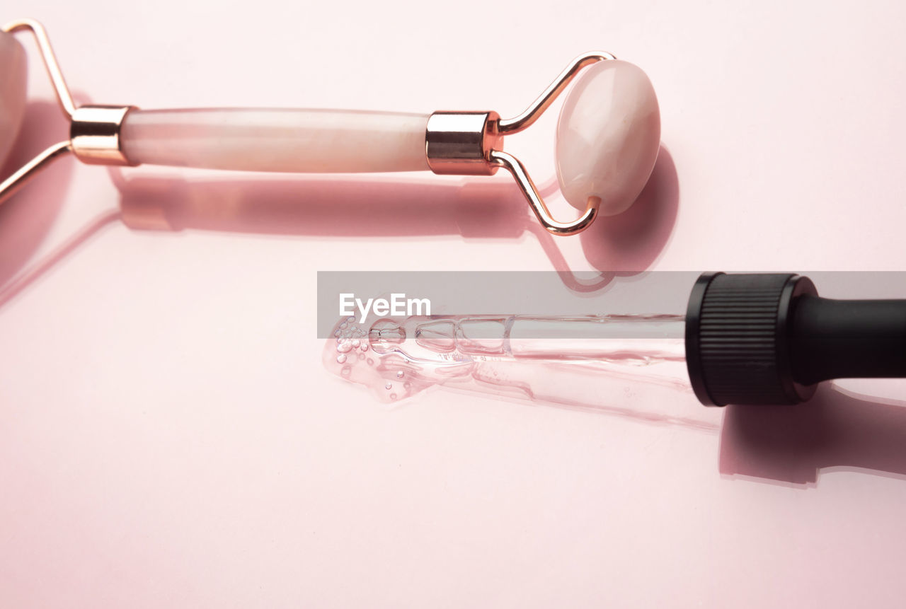 Roller and beauty product on a pink background. dropper with serum, oil or other cosmetic product