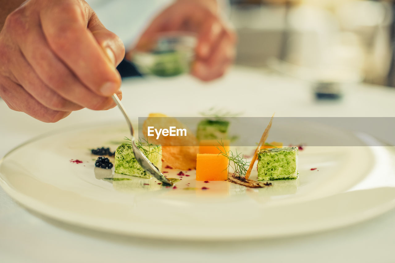 Close-up of man preparing food on plate