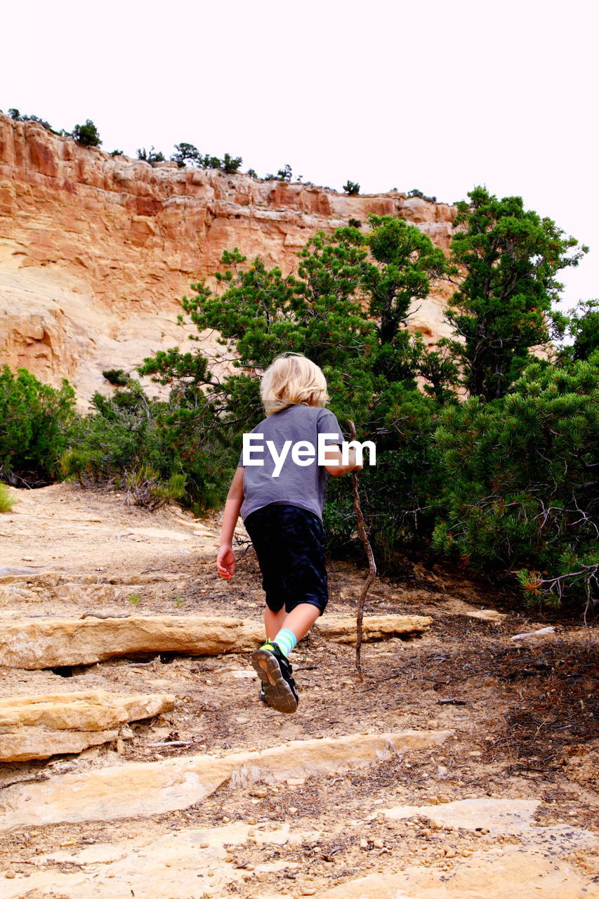 Rear view of boy hiking on rock formation at dinosaur national monument