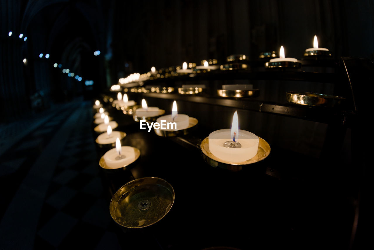 5 rows of prayer candles run from right to left in this wide angle photo from a cathedral