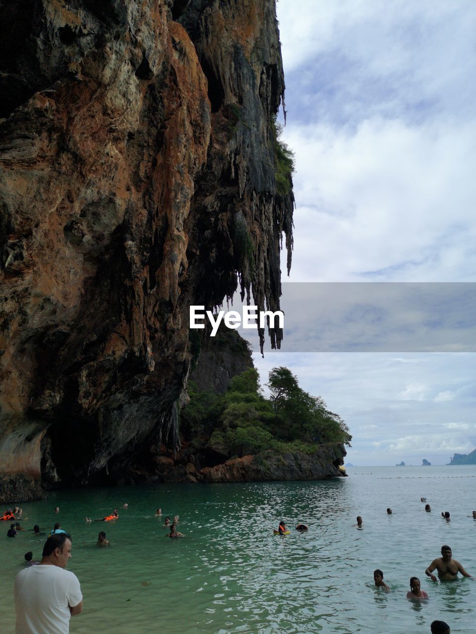 PEOPLE SWIMMING IN SEA AGAINST ROCK FORMATION