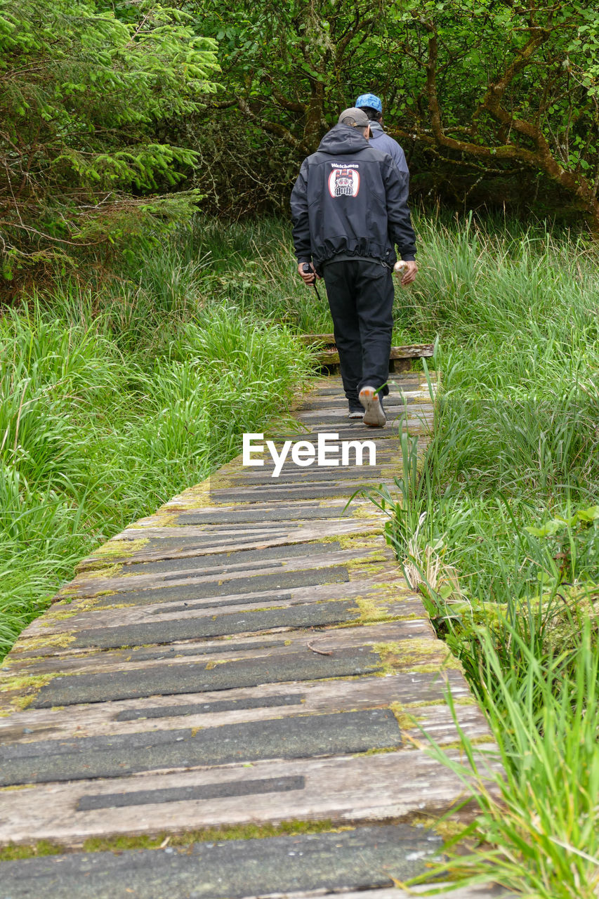 REAR VIEW OF A MAN WALKING ON STEPS