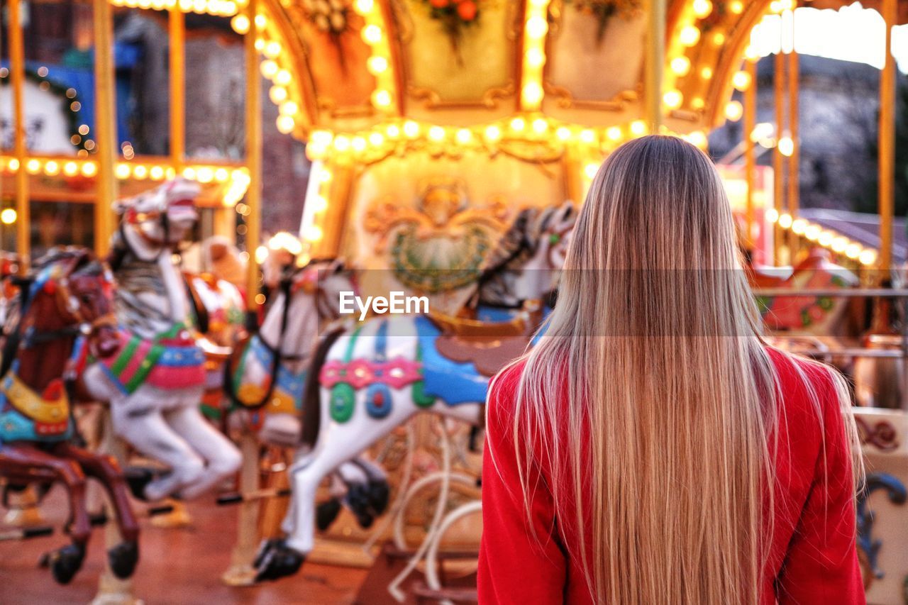 Rear view of woman standing against carousel