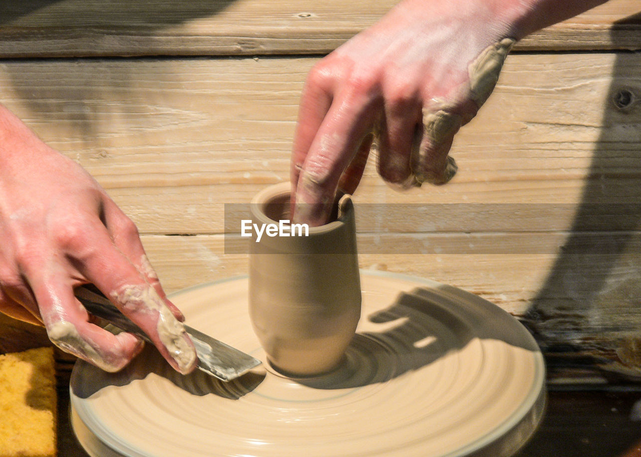 Cropped hands of man making pot in workshop