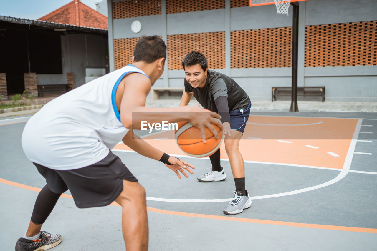 Friends playing basketball at court