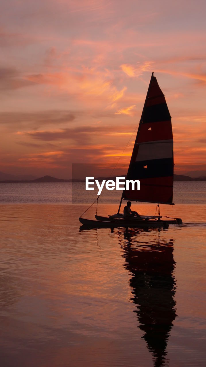 Silhouette man in boat on sea against sky during sunset