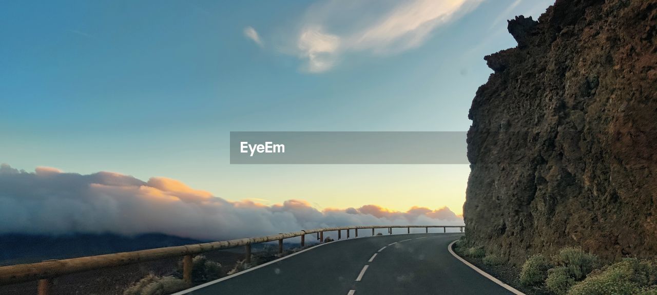 Road by mountains against sky during sunset