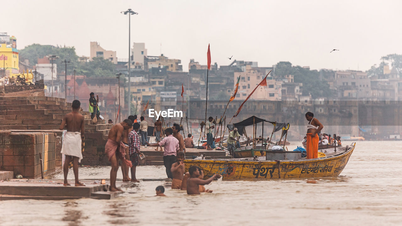 PEOPLE ON BOATS IN SEA AGAINST SKY