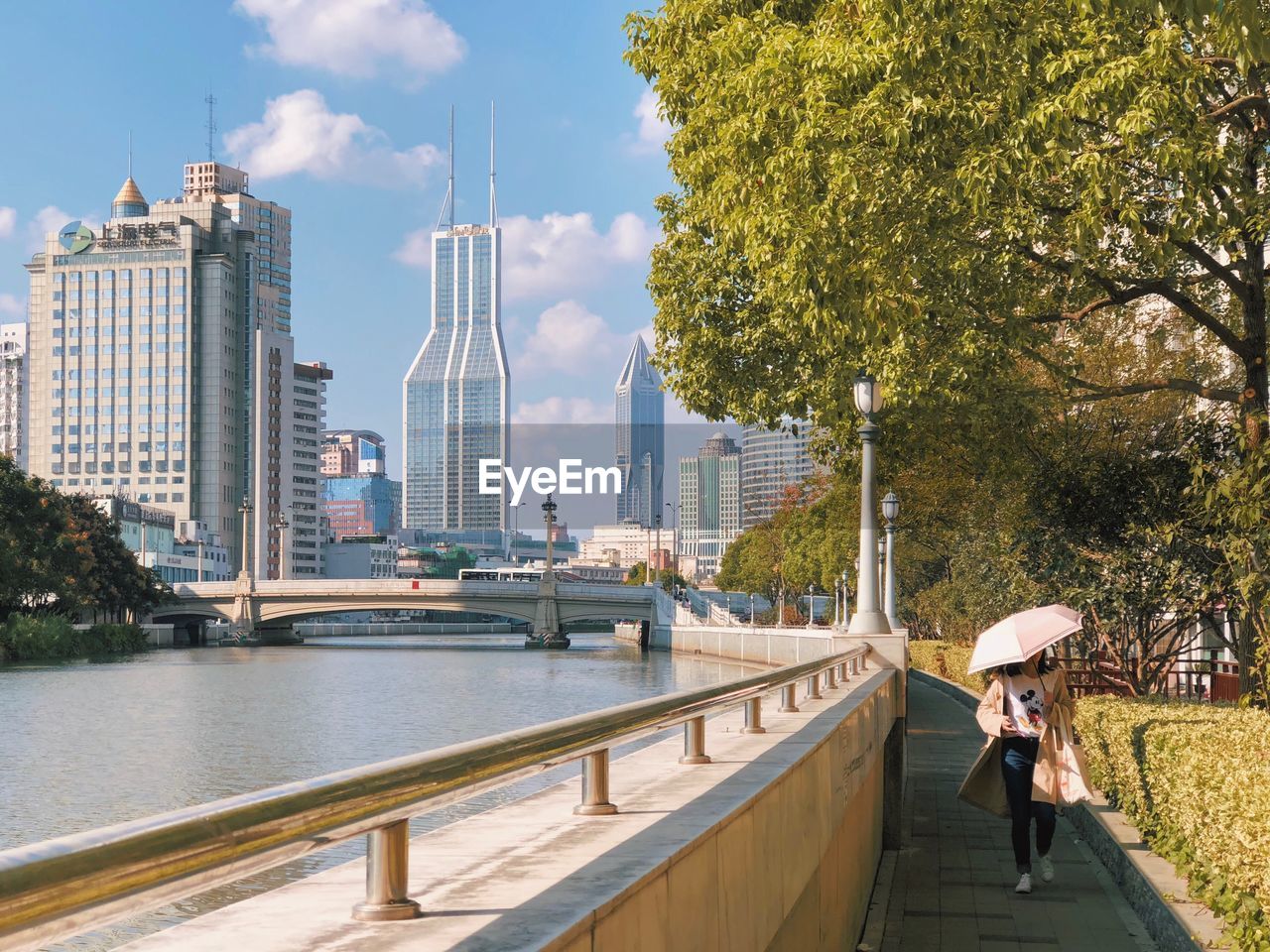 PEOPLE ON BRIDGE OVER RIVER AMIDST BUILDINGS IN CITY