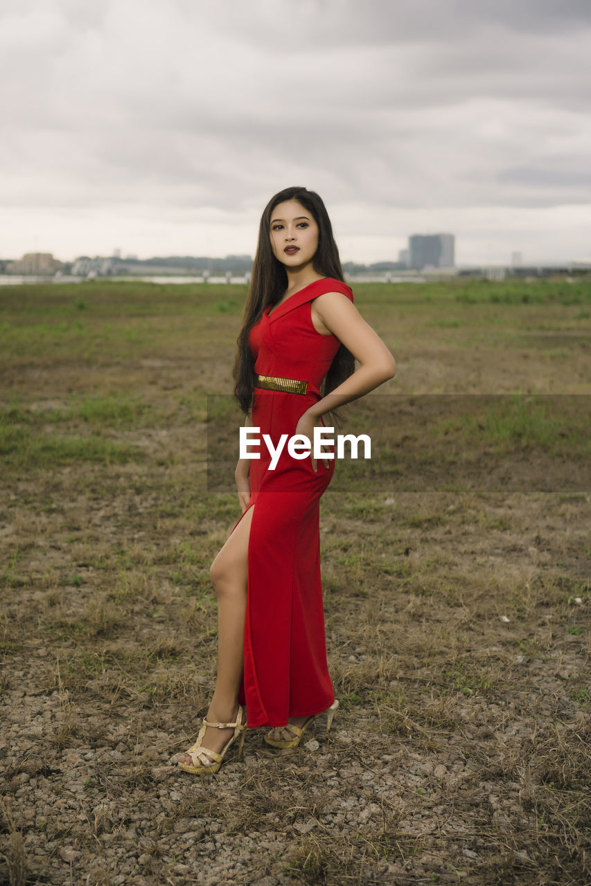 PORTRAIT OF WOMAN STANDING ON FIELD