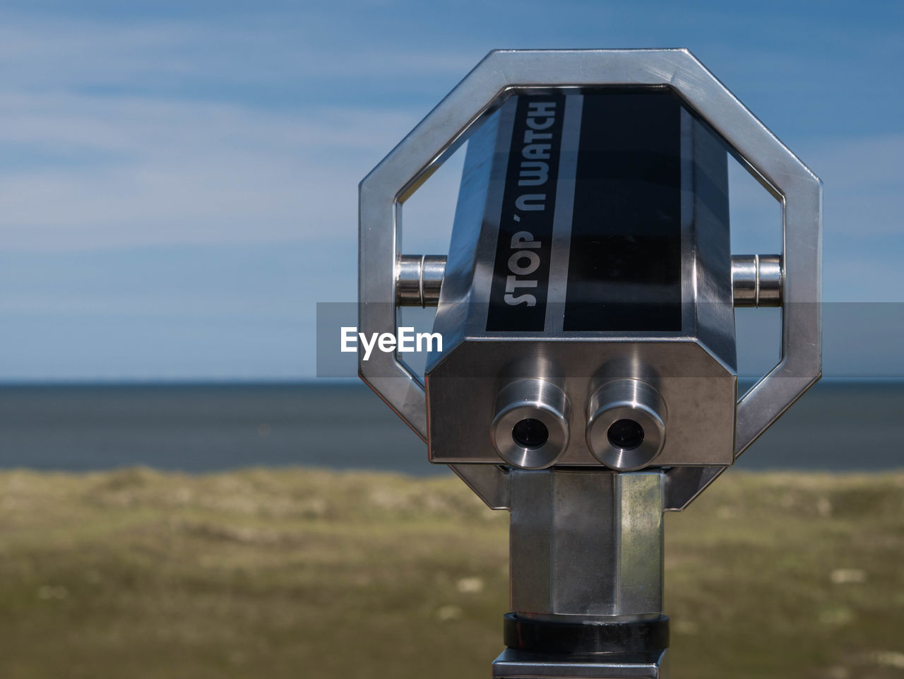 CLOSE-UP OF COIN-OPERATED BINOCULARS ON SEA AGAINST SKY