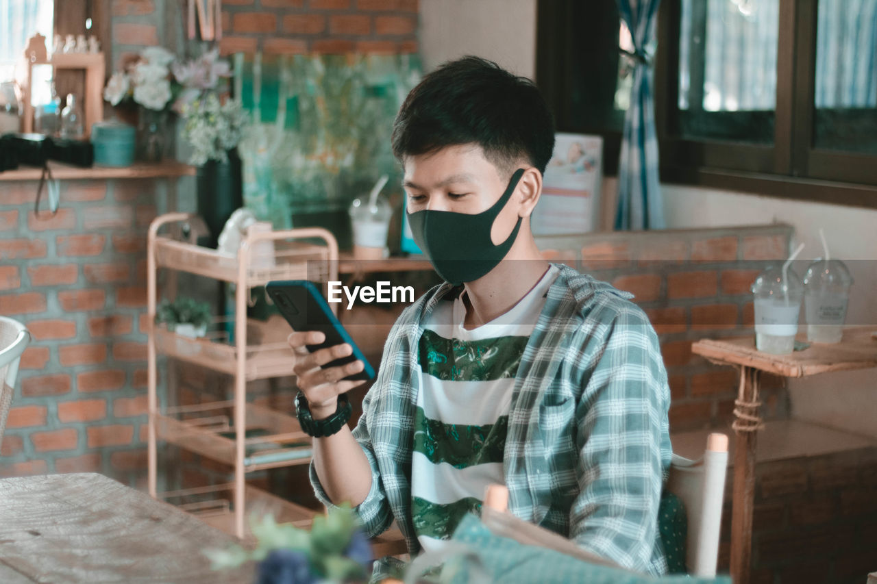 Young man using mobile phone at table