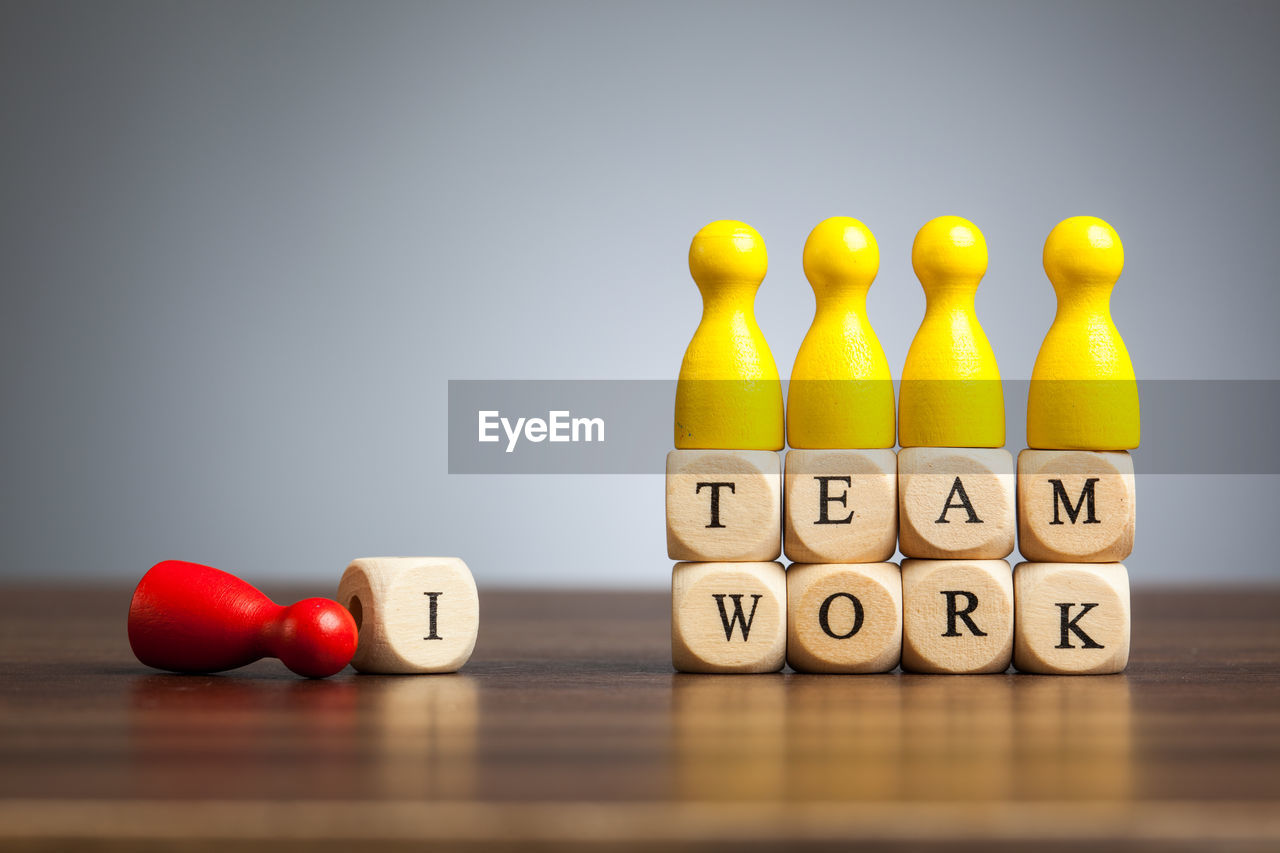 Close-up of yellow tokens with teamwork text on table against gray background