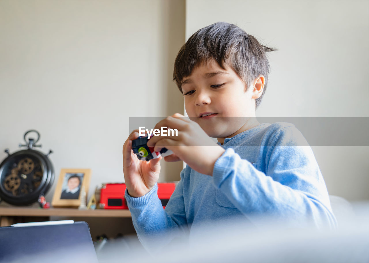 Portrait of boy holding camera at home