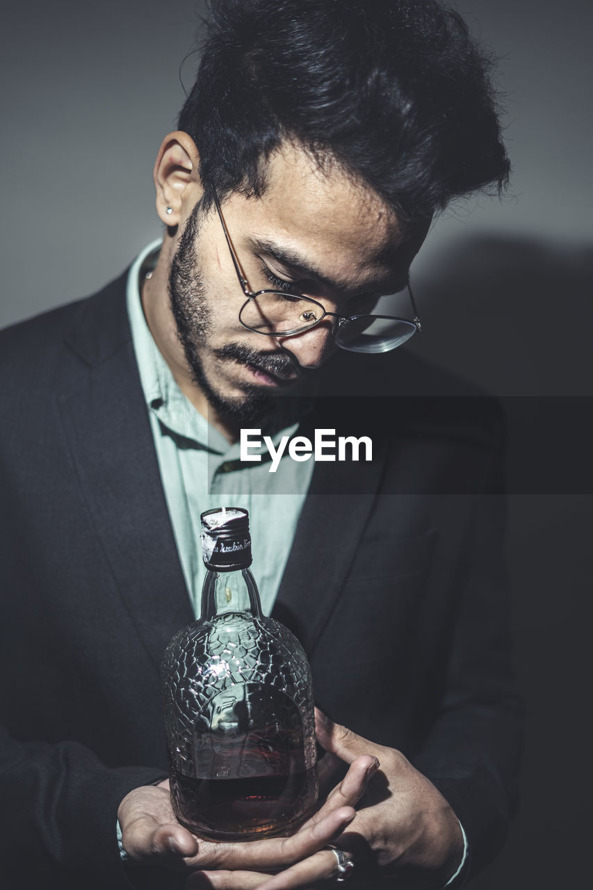 Young man wearing eyeglasses holding bottle