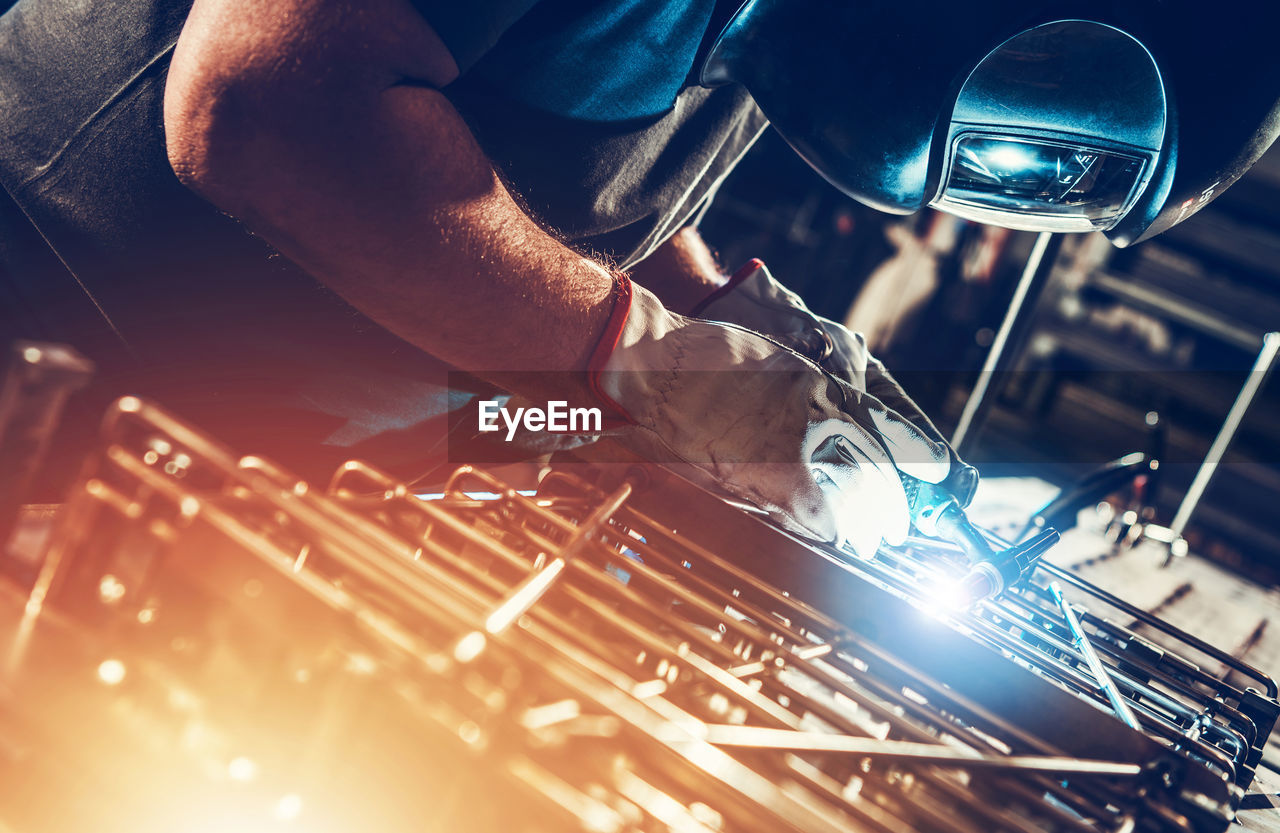 midsection of man welding sparks at workshop