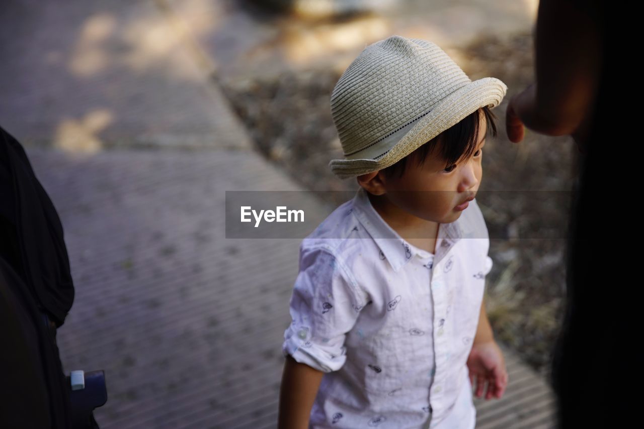 High angle view of boy wearing hat while standing on footpath