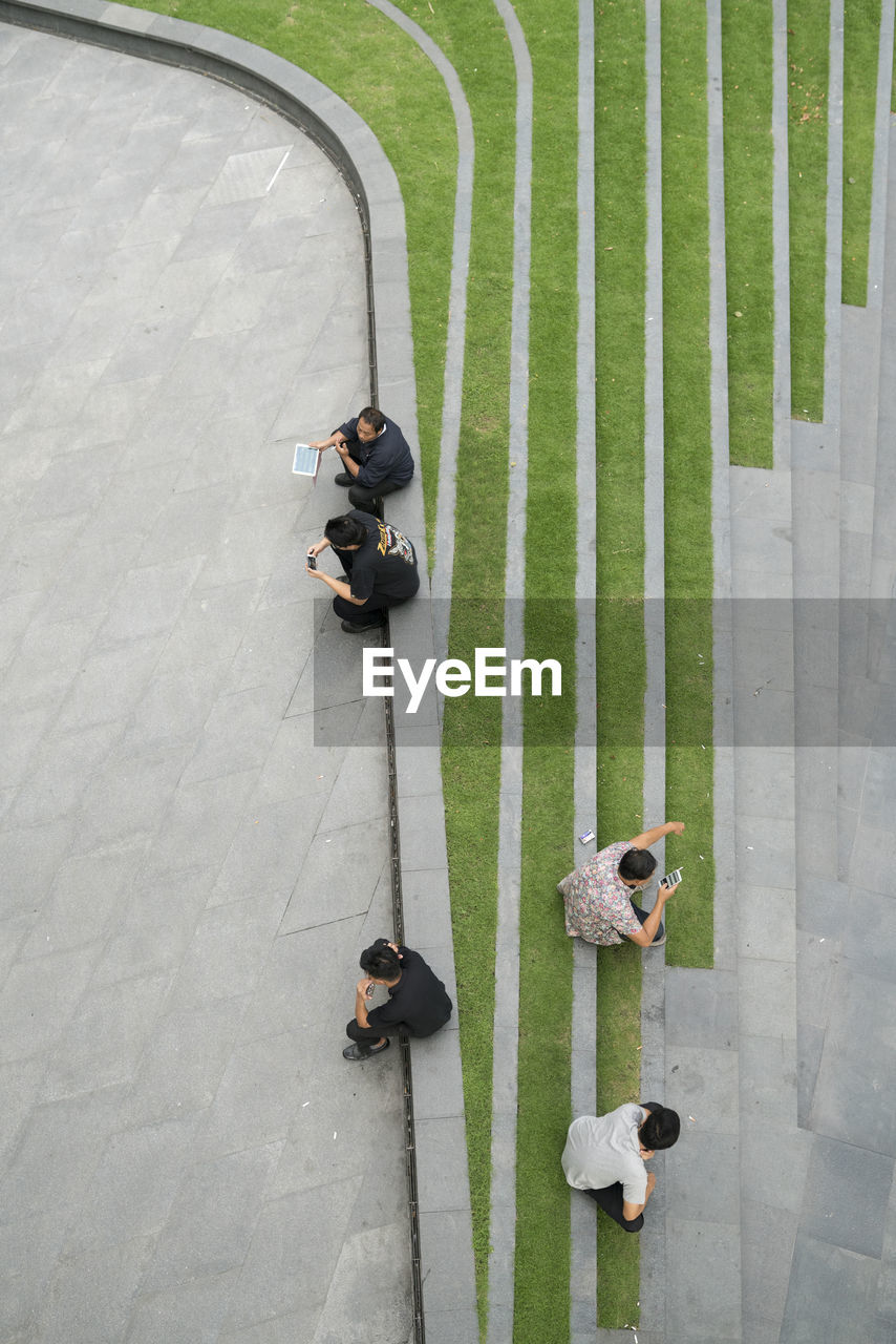 HIGH ANGLE VIEW OF PEOPLE ON FOOTPATH AMIDST GREEN WALL