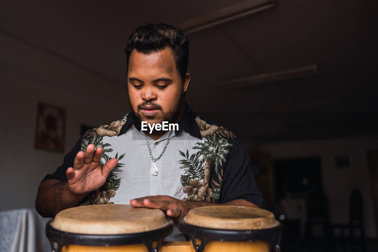 Black male musician in casual clothes sitting on chair with drums