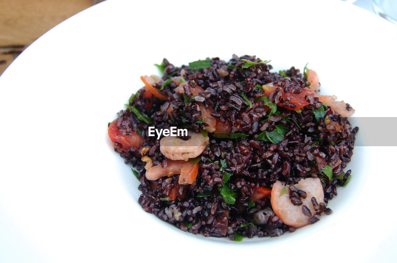 Close-up of black rice with prawns in plate