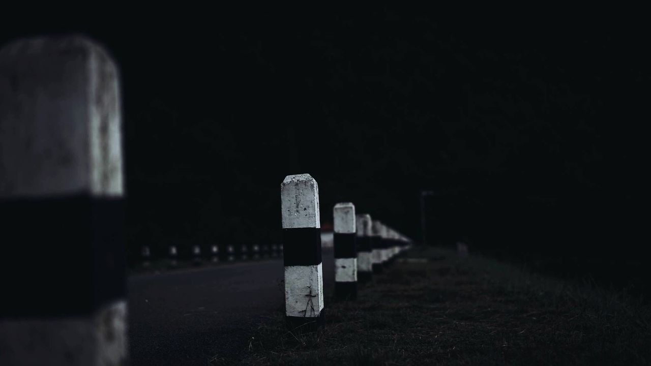 Close-up of bollards by road against sky at night