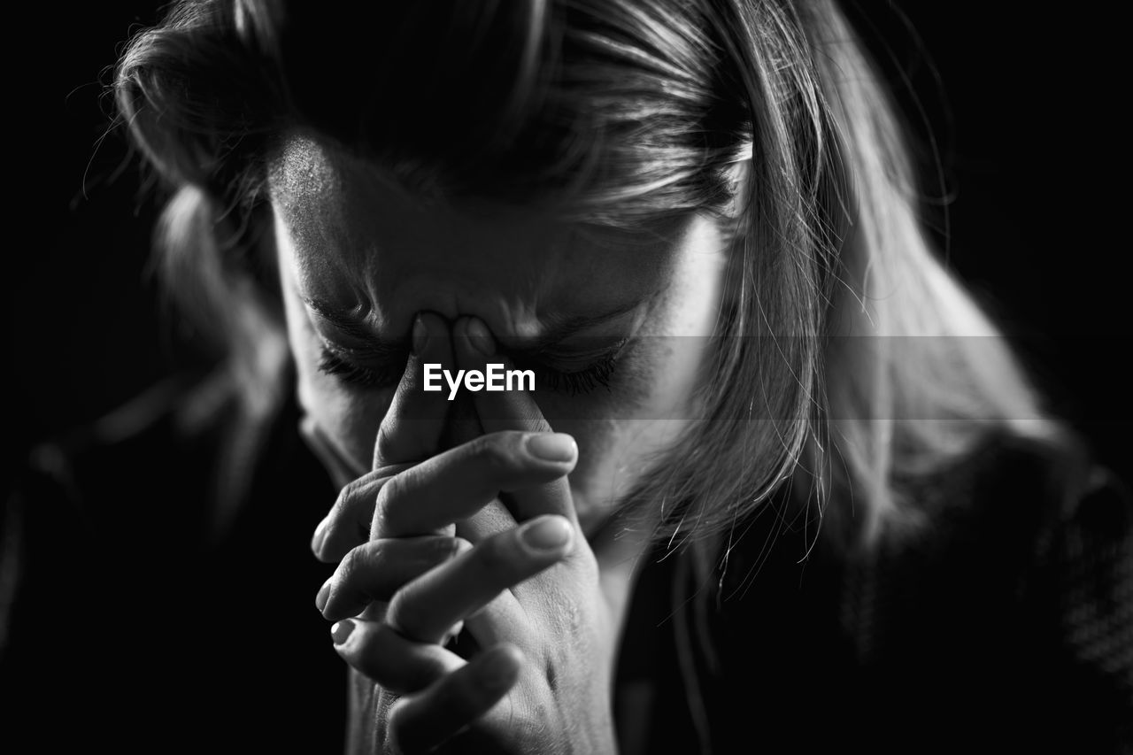 Close-up of depressed woman against black background